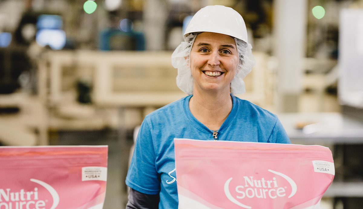 photo of a woman standing beside bags of NutriSource pet food on the line at Tuffy's